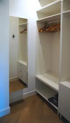 a walk in closet with white cabinets and wood floors at Daina Apartments Self check-in in Vilnius