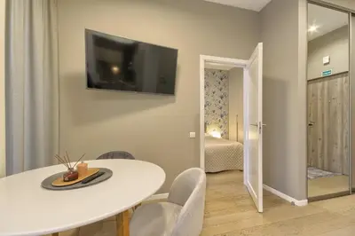 a dining room with a white table and a television on the wall at Ruby Rest in Druskininkai