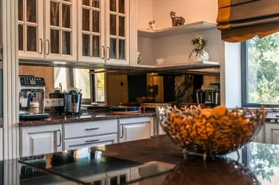 a kitchen with white cabinets and a bowl of fruit on a counter at Paežerės istorijos near Druskininkai in Veršiai