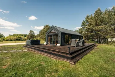 a house with a deck in a field at Paežerės istorijos near Druskininkai in Veršiai