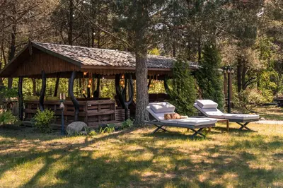 a gazebo with two chairs and a dog laying on a bench at Paežerės istorijos near Druskininkai in Veršiai