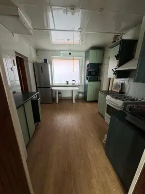 a kitchen with green cabinets and a wooden floor at Svečių Namai Darželis in Šiauliai
