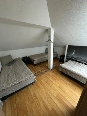 an attic room with two beds and a wooden floor at Svečių Namai Darželis in Šiauliai