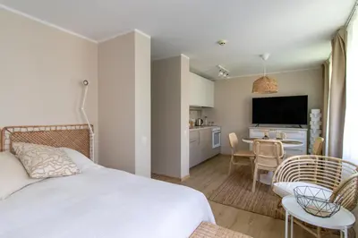 a bedroom with a bed and a kitchen with a table at Harmony Hill Apartments in Druskininkai