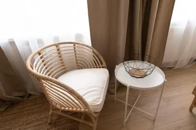 a chair and a side table in front of a window at Harmony Hill Apartments in Druskininkai