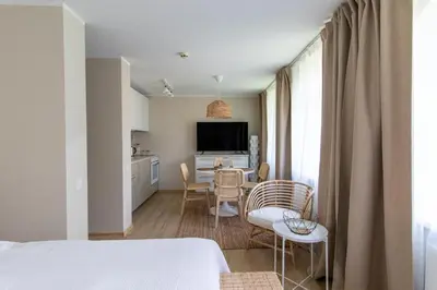a bedroom with a table and chairs and a kitchen at Harmony Hill Apartments in Druskininkai