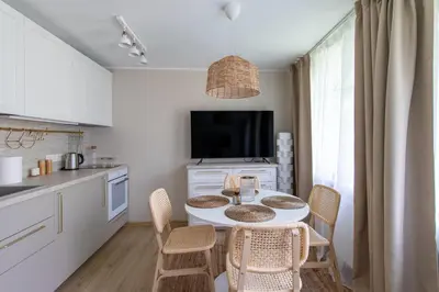 a kitchen with a table with chairs and a tv at Harmony Hill Apartments in Druskininkai