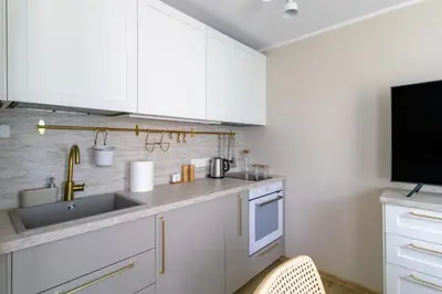 a kitchen with white cabinets and a sink at Harmony Hill Apartments in Druskininkai