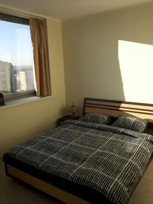 a bedroom with a bed with a plaid blanket and a window at Centro apartamentai - Vingio apartamentai in Vilnius