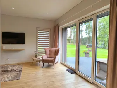 a living room with a chair and a sliding glass door at Sofijos Slėnis in Pakniškiai