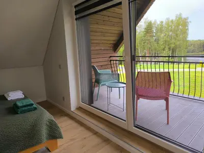 a bedroom with a large window with a bed and chairs at Sofijos Slėnis in Pakniškiai