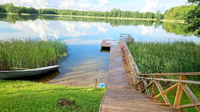 a wooden dock with a boat next to a lake at Sofijos Slėnis in Pakniškiai