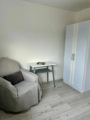 a living room with a table and a chair and a bed at Vivist apartments in Druskininkai