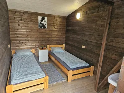 two beds in a room with wooden walls at Merkioaidas in Sližiūnai