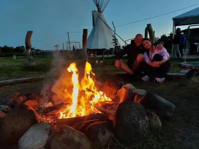 two people sitting around a fire in a field at Merkioaidas in Sližiūnai