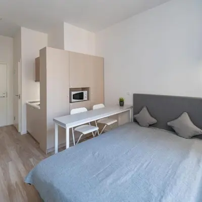 a bedroom with a bed and a desk with a microwave at Studio on Laisves Aleja, Central Kaunas - Self Check In in Kaunas