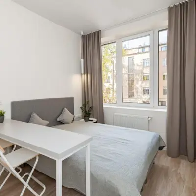 a bedroom with a bed and a table and window at Studio on Laisves Aleja, Central Kaunas - Self Check In in Kaunas