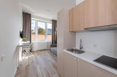 a kitchen with a sink and a living room at Studio on Laisves Aleja, Central Kaunas - Self Check In in Kaunas