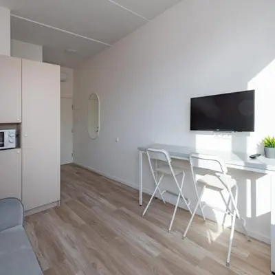 a living room with a table with chairs and a tv at Studio on Laisves Aleja, Central Kaunas - Self Check In in Kaunas