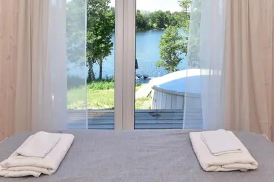 a bedroom with two towels on a bed with a large window at Pineplace trio BANGA in Žaugėdai