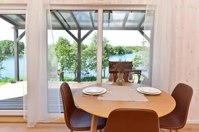 a dining room table with chairs and a large window at Pineplace trio BANGA in Žaugėdai