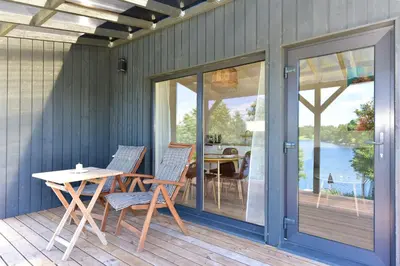 a patio with a table and chairs on a deck at Pineplace trio BANGA in Žaugėdai