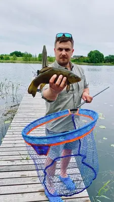 a man holding a fish in front of a boat at Pineplace trio BANGA in Žaugėdai