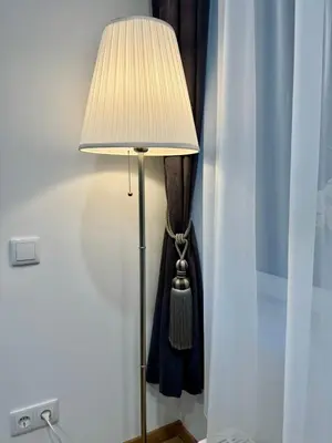 a lamp with a white shade next to a curtain at UAB DU PROCENTAI nt in Šiauliai