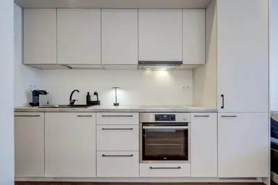 a white kitchen with white cabinets and a sink at Modern Apartment near Old Town & River in City Center in Vilnius