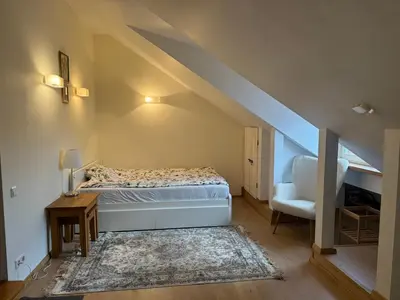 a small bedroom with a bed and a chair at Old Town loft in Vilnius