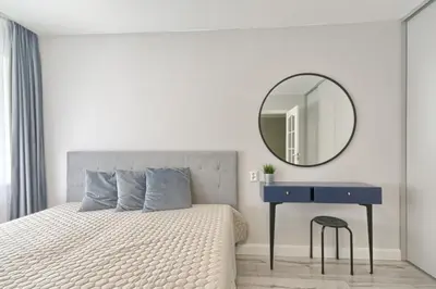 a bedroom with a bed with a blue table and a mirror at Apartamentai Vilniaus alėjoje in Druskininkai