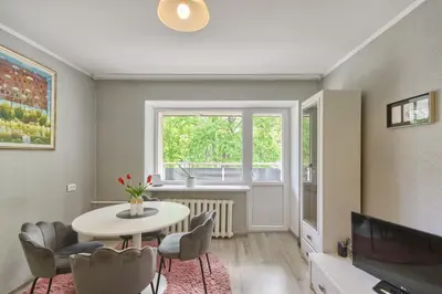 a living room with a table and chairs and a window at Apartamentai Vilniaus alėjoje in Druskininkai