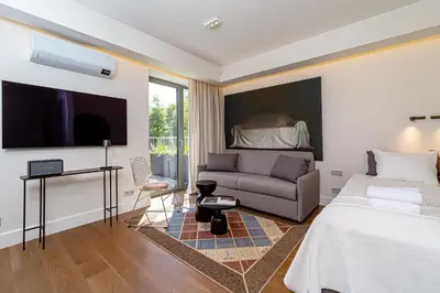 a bedroom with a bed and a couch and a tv at cohost I New Apt w-Balcony I Air Condition I Free Parking & Netflix I By Botanical Park in Kaunas