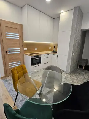 a kitchen with a glass table and a yellow chair at Kestutis Luxury Apartment in Šiauliai