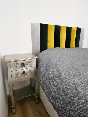 a bed with a nightstand next to a bed with a striped head board at Kestutis Luxury Apartment in Šiauliai