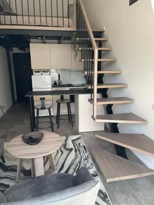 a living room with a spiral staircase and a table at Mini loft in Kaunas
