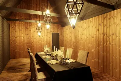a dining room with a table and chairs and lights at Sodyba Mėnulio Slėnis in Padubysys