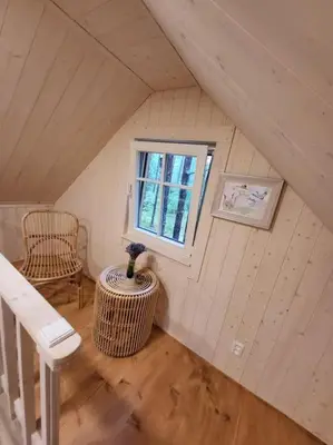a small attic room with a window and a table at Ramus poilsis miške su kedro pirtimi ir kubilu in Marcinkonys