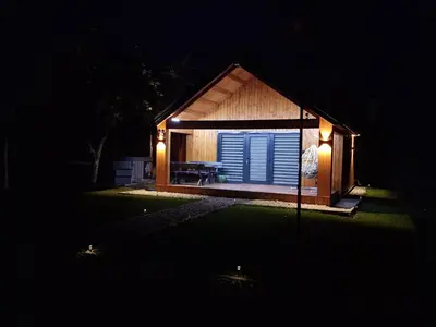 a small house with lights on it at night at Naujai įrengtas atostogų namelis su kubilu ir pirtimi papildomai in Anykščiai