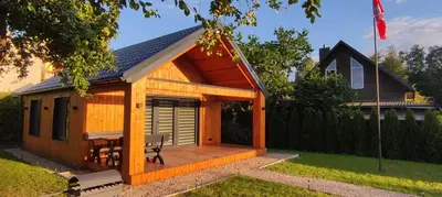 a wooden cabin with a deck in a yard at Naujai įrengtas atostogų namelis su kubilu ir pirtimi papildomai in Anykščiai