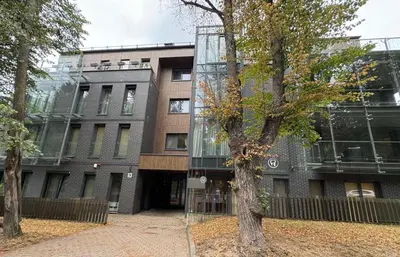 a glass building with a tree in front of it at Apartamentai prie Kalnų parko in Vilnius