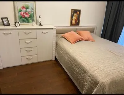 a bedroom with a dresser and a bed with an orange pillow at Apartamentai prie Kalnų parko in Vilnius