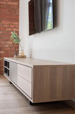 a wooden dresser in a living room with a mirror at Rossak apartment 1 in Panevėžys