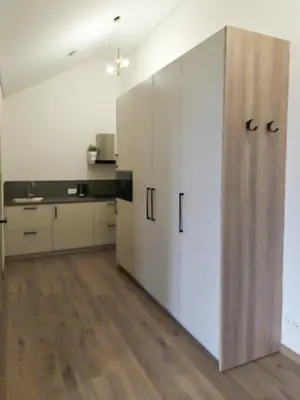 a kitchen with white cabinets and a wooden floor at Rossak apartment 1 in Panevėžys