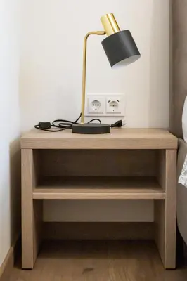 a bedside table with a lamp on top of it at Rossak apartment 2 in Panevėžys