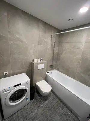 a bathroom with a toilet and a washing machine at Bright and cozy place to stay in Vilnius
