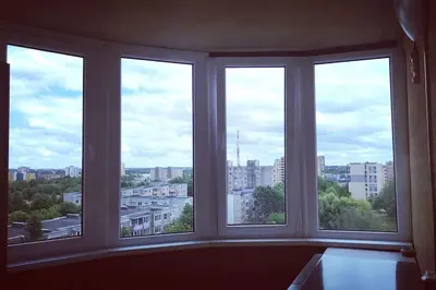 a room with three windows with a view of a city at Lyra cozy large apartment in Šiauliai