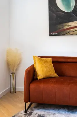 a brown couch with a yellow pillow in a living room at SongInn Lake Apartment in Zarasai