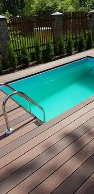 a swimming pool on a wooden deck at Jaukūs namai Kulautuvoje in Kulautuva