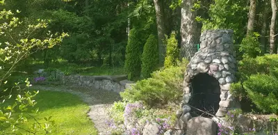 a stone oven in a garden with flowers and trees at Jaukūs namai Kulautuvoje in Kulautuva